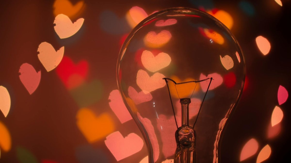 Light bulb with colorful heart-shaped bokeh creating a warm and romantic mood.
