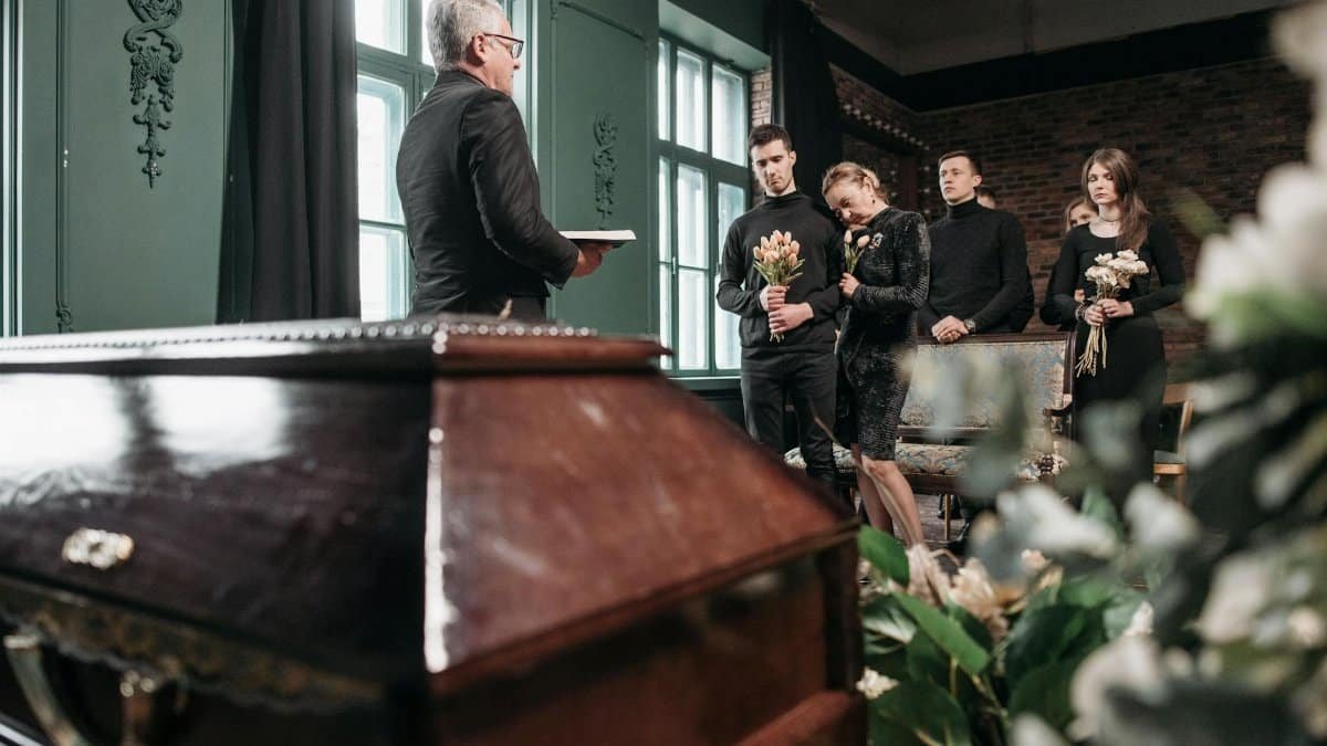 Attendees pay final respects at a solemn funeral ceremony indoors.