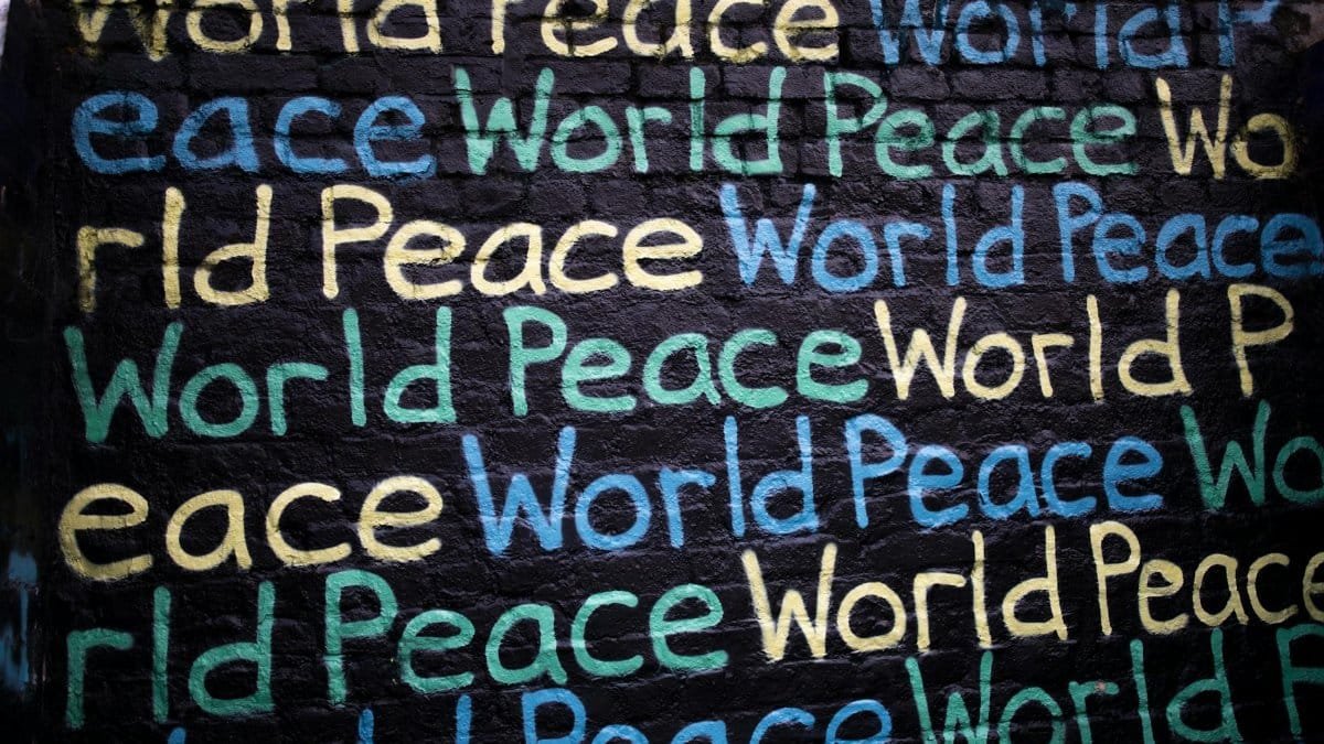 Colorful graffiti on a brick wall repeating the phrase 'World Peace.'