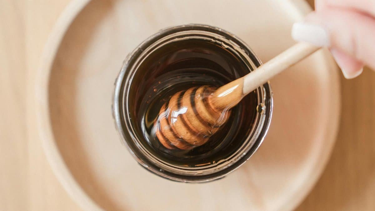 Top view of honey dipper in a jar, perfect for culinary and food themes.