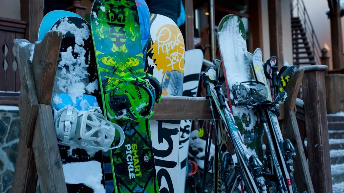 Snowboards and skis lined up outdoors at a winter ski lodge, showcasing vibrant designs.