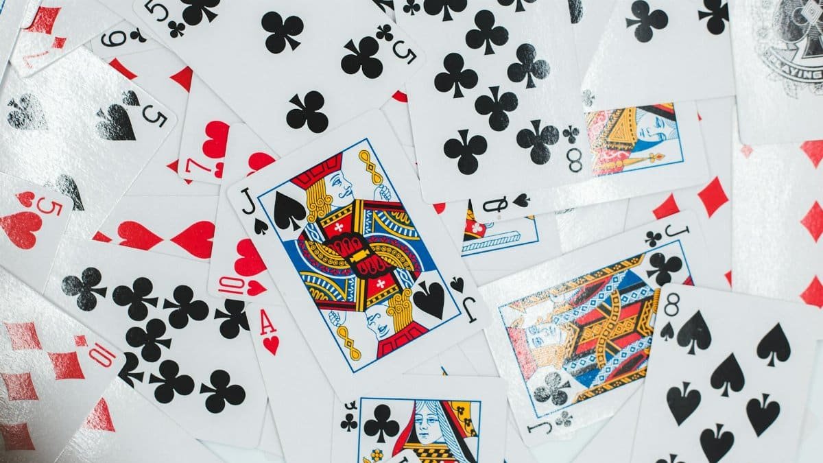 Colorful assortment of playing cards laid out in a chaotic pattern, showcasing various suits and face cards.