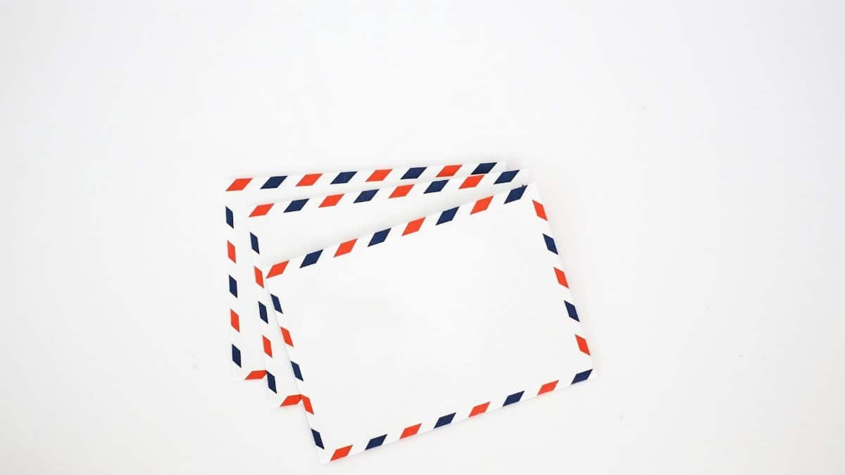 Top view set of white envelops with striped red and blue edges placed on plain white background