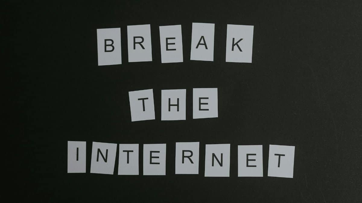 Conceptual flat lay of 'Break the Internet' message with white letters on a black background.