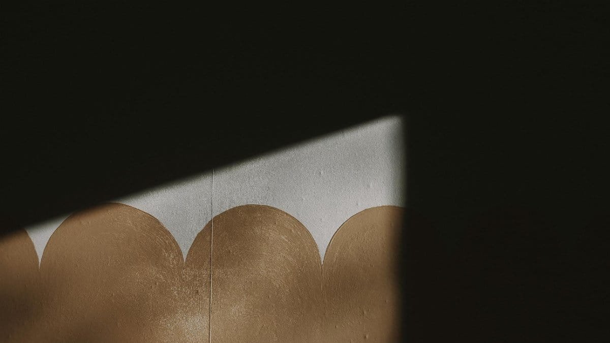 A dramatic play of light and shadow on a textured wall with a unique geometric pattern.