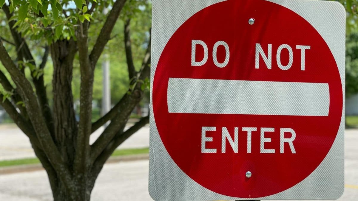Close-up of a red do not enter sign in a leafy outdoor environment indicating no entry.