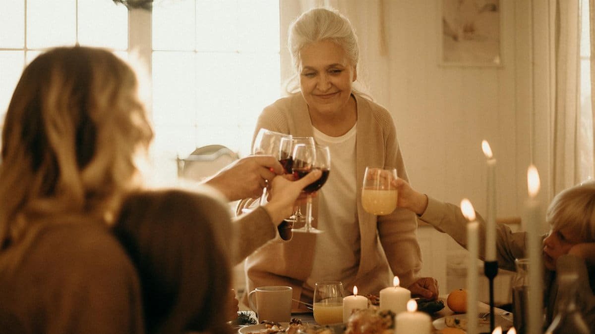 A joyful family dinner where people toast with various drinks surrounded by candlelight.