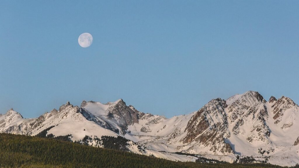 Stunning view of snow-covered mountains under a full moon in Colorado's winter landscape.