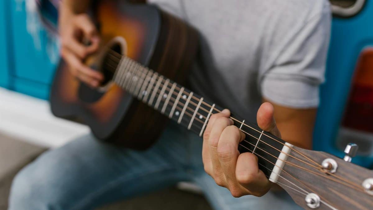 Close-up of a man playing an acoustic guitar outside, adding a musical vibe.