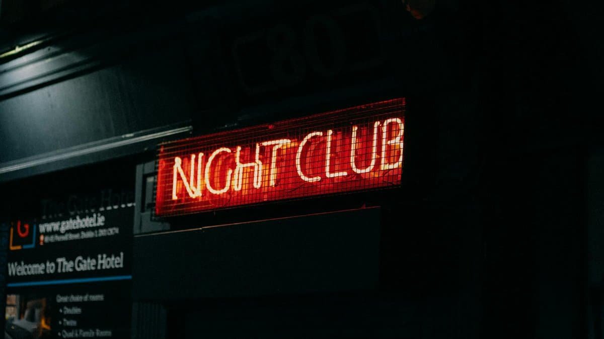 Close-up of a neon-lit 'Night Club' sign in a dark urban setting capturing nightlife ambiance.