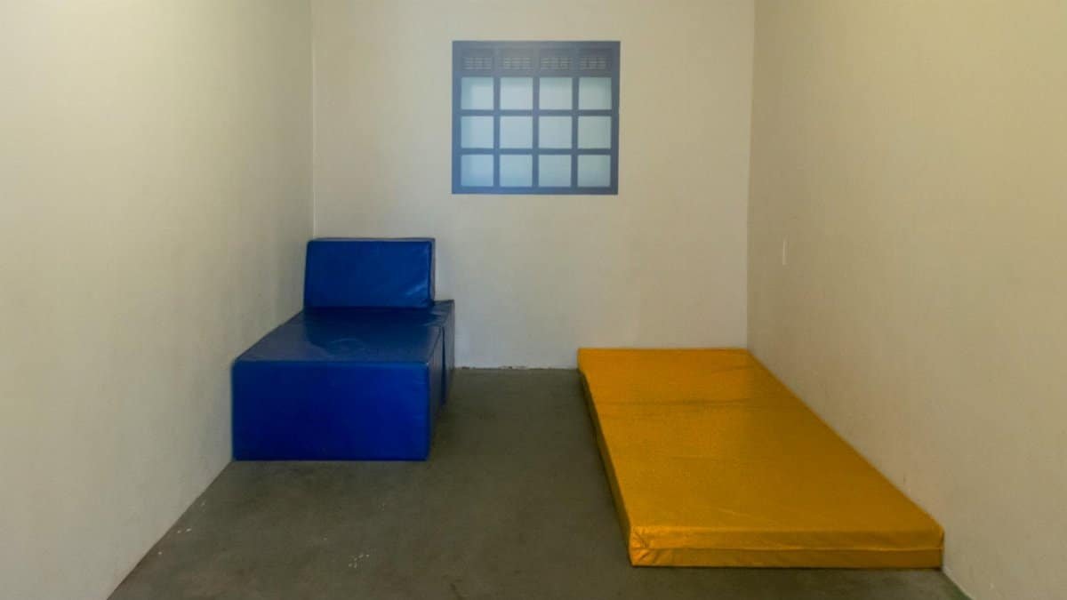 A sparse room with colorful simple seating arrangements and a small window.