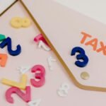 Bright plastic numbers scattered over a tax envelope, symbolizing accounting and finance concepts.