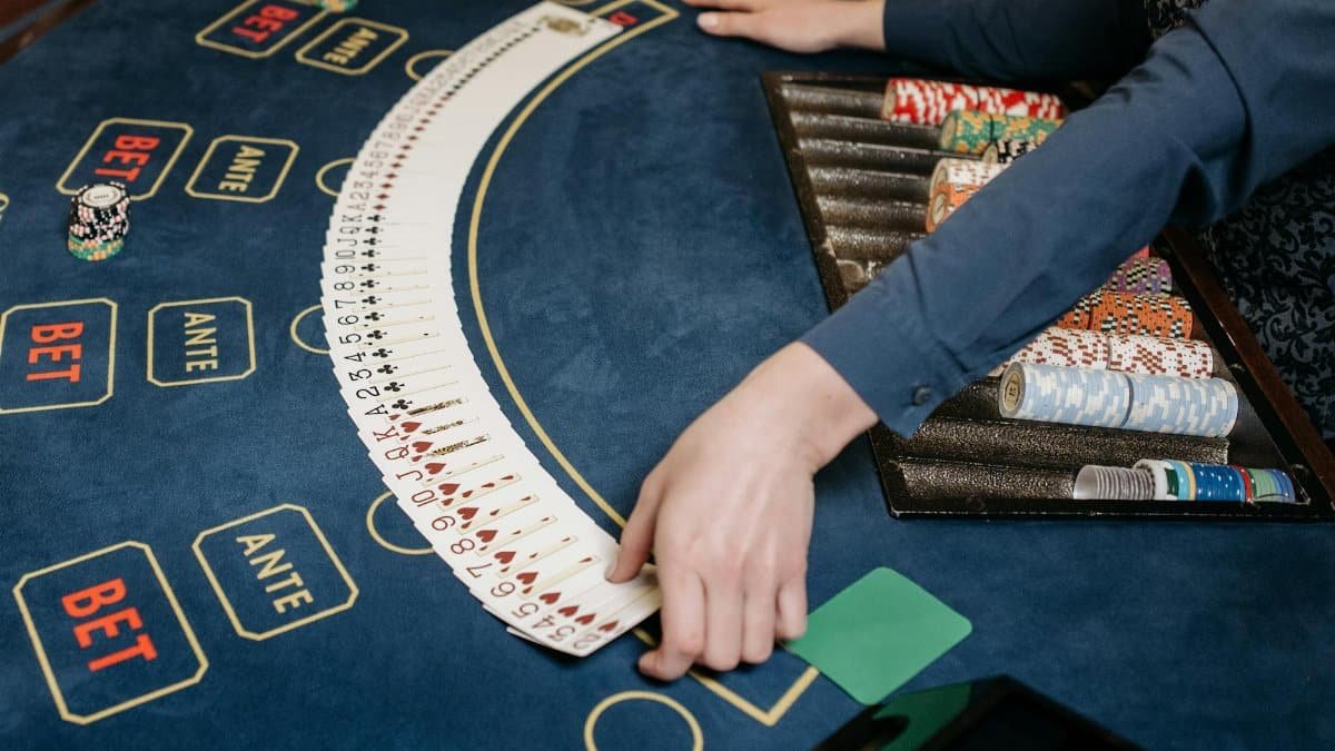 A casino dealer organizing playing cards on a gaming table with chips. Indoors setting.