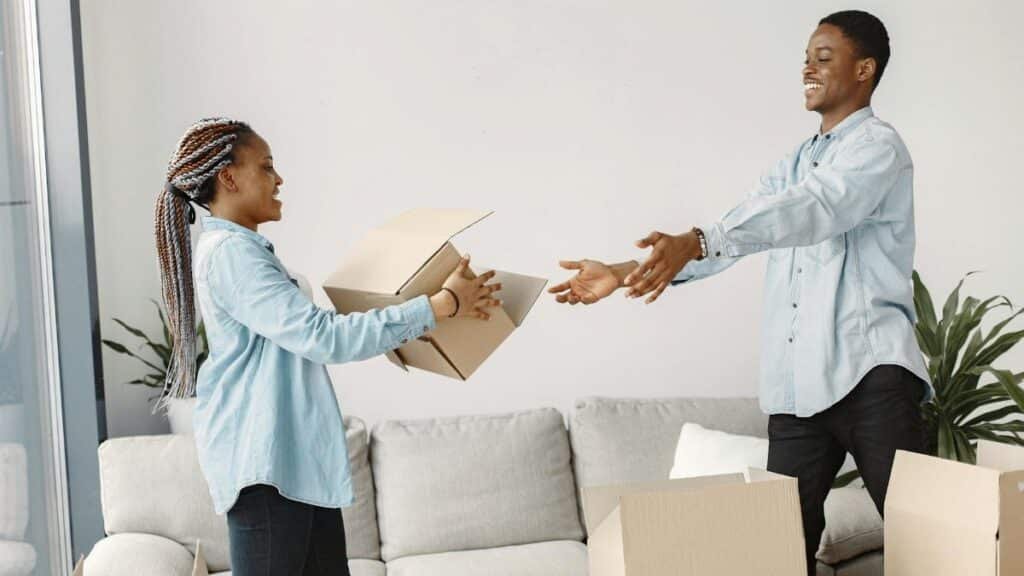 Happy couple exchanging boxes while moving into their new modern living room.