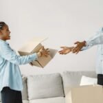 Happy couple exchanging boxes while moving into their new modern living room.