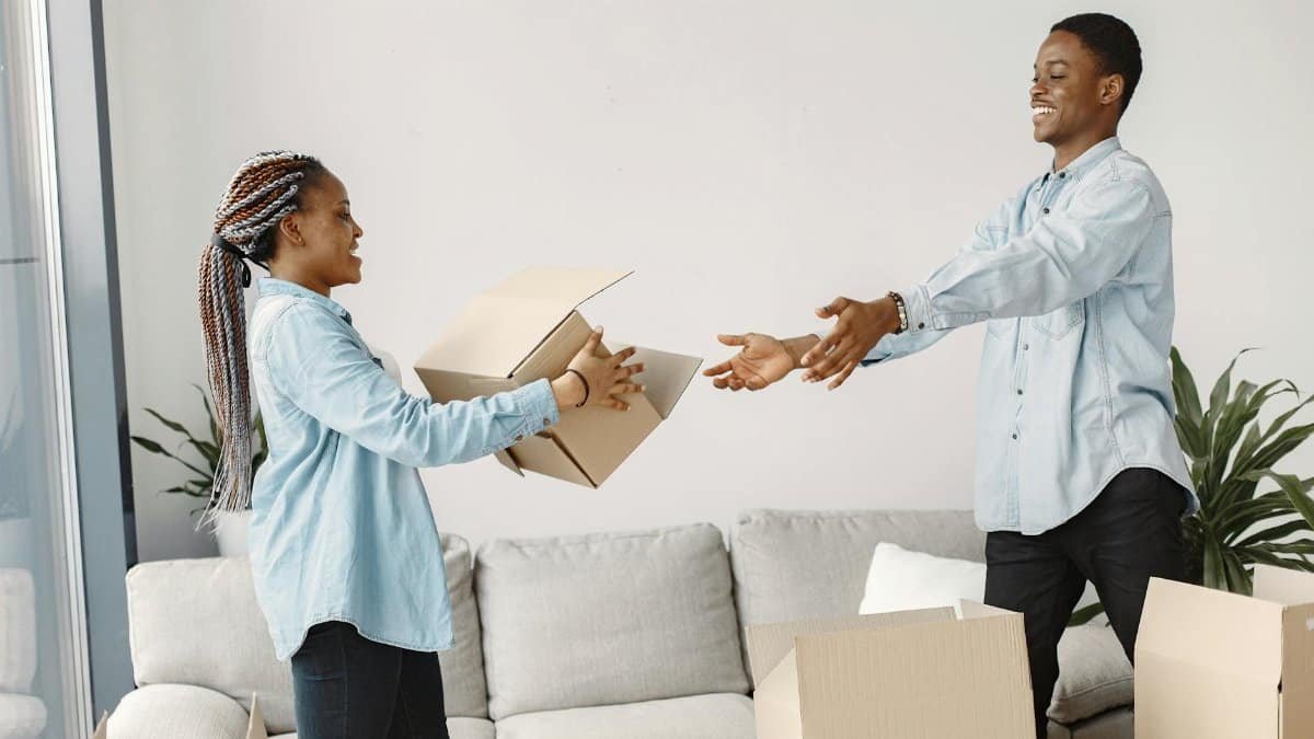 Happy couple exchanging boxes while moving into their new modern living room.