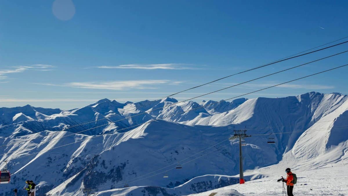 Breathtaking view of skiers and snow-covered peaks in Gudauri, Georgia, a popular winter sports destination.