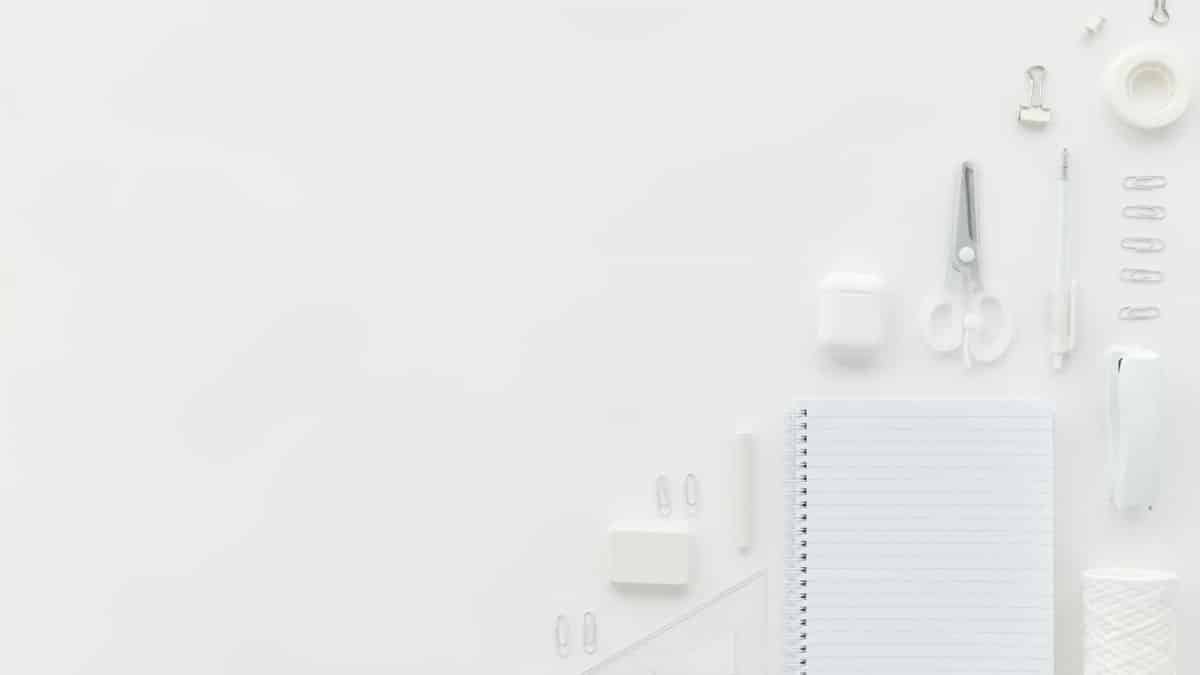Flat lay of white stationary items on a minimalist office desk with ample copy space.