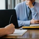 Crop anonymous female filling questionnaire when applying for job sitting in employer office