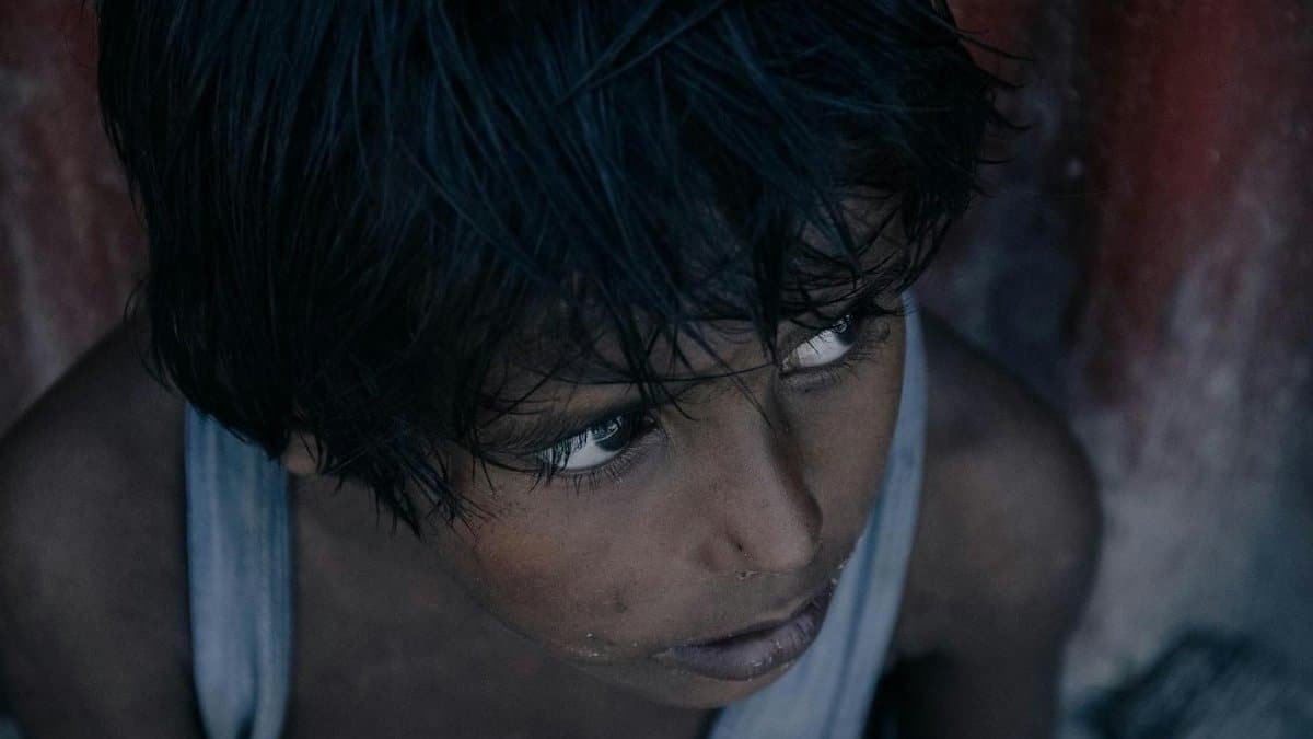Close-up of a thoughtful child gazing upward in a gritty urban setting, emotively captured.