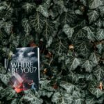 A novel titled 'Where Are You?' lies among dense ivy leaves in a garden setting.