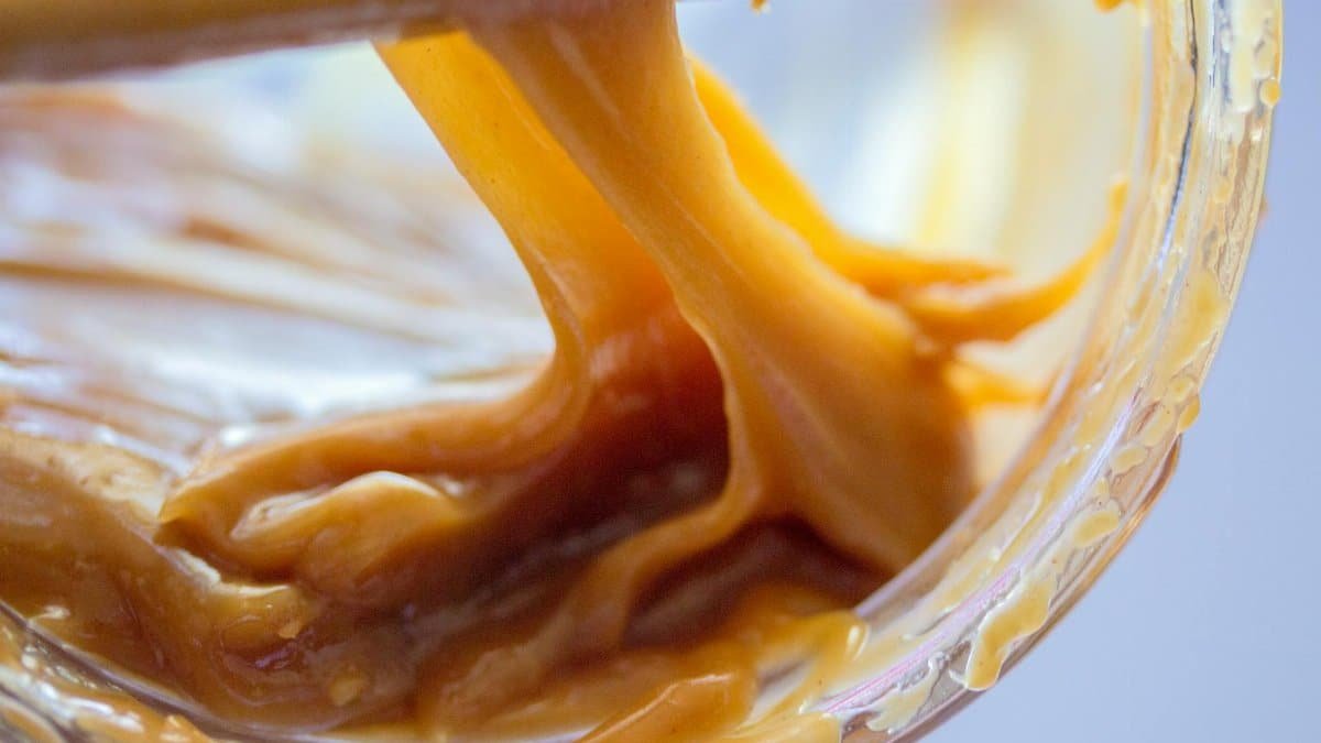 A detailed close-up image of smooth, gooey caramel showcasing its rich texture and color.