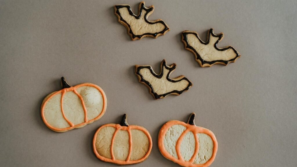 Festive Halloween pumpkin and bat-shaped cookies on a gray background, perfect for holiday treats.