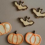 Festive Halloween pumpkin and bat-shaped cookies on a gray background, perfect for holiday treats.