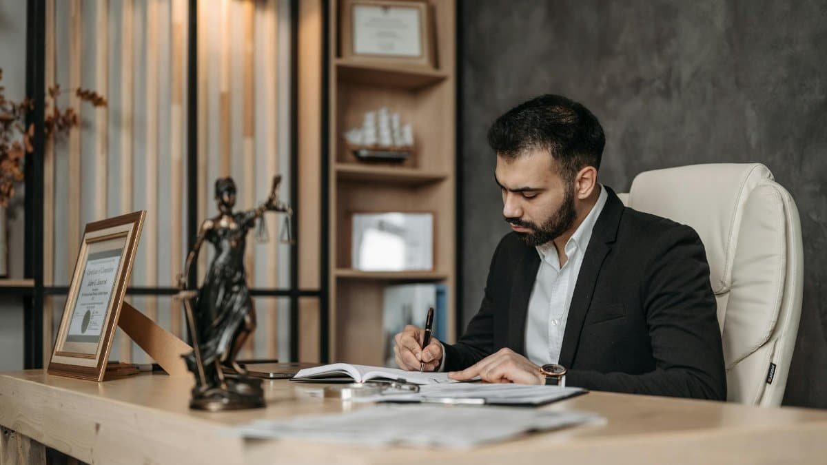 A focused lawyer in an office setting writing and reviewing legal documents, symbolizing expertise and professionalism.