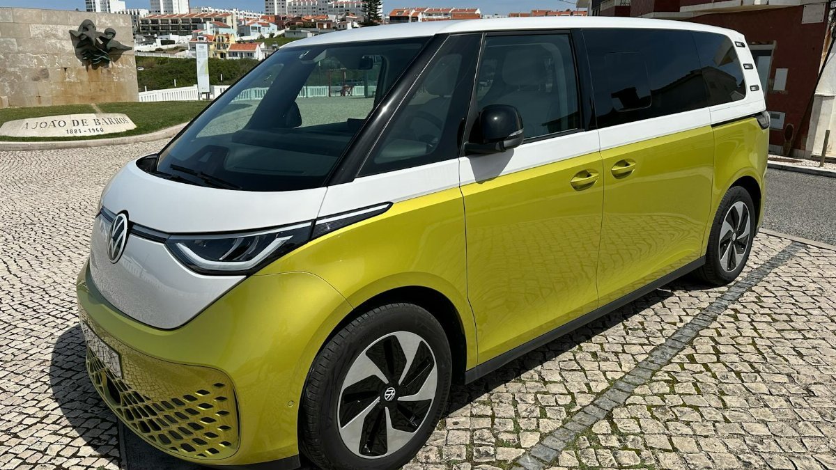 Volkswagen ID. Buzz parked on cobblestone street in scenic Portuguese town under clear skies.