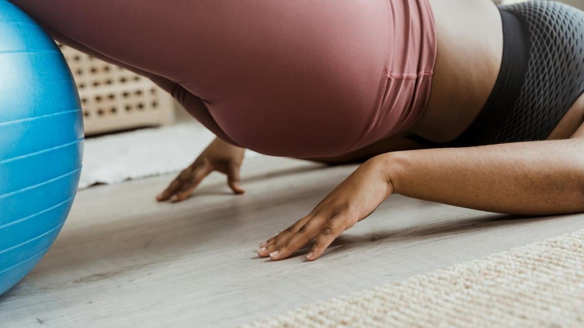 Close-up of a woman working out indoors using a fitness ball. Focus on balance and core strength.