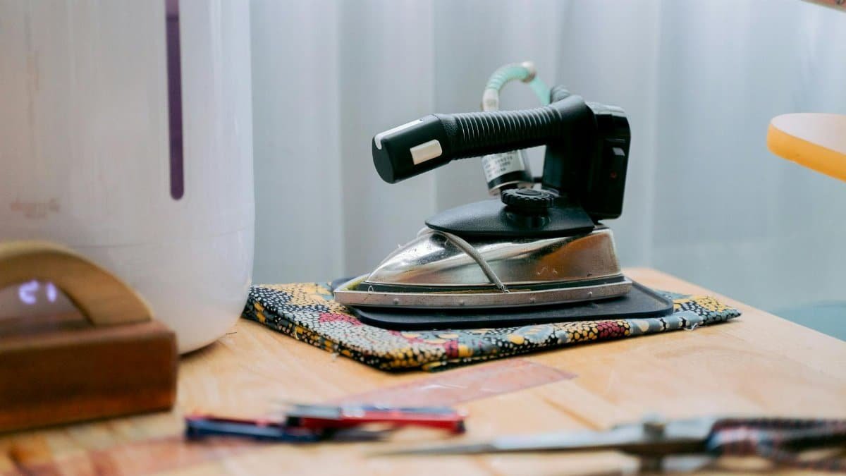 Retro iron on a wooden table beside other household items, evoking nostalgia.