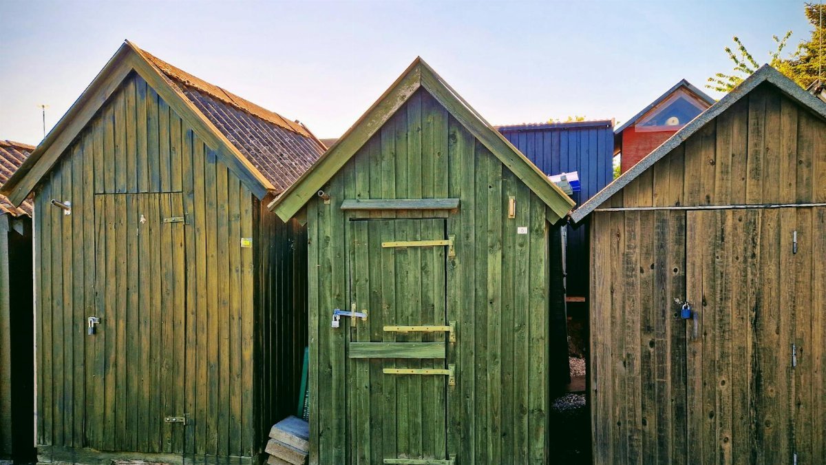 Colorful wooden sheds in Assens, Denmark under clear summer sky.