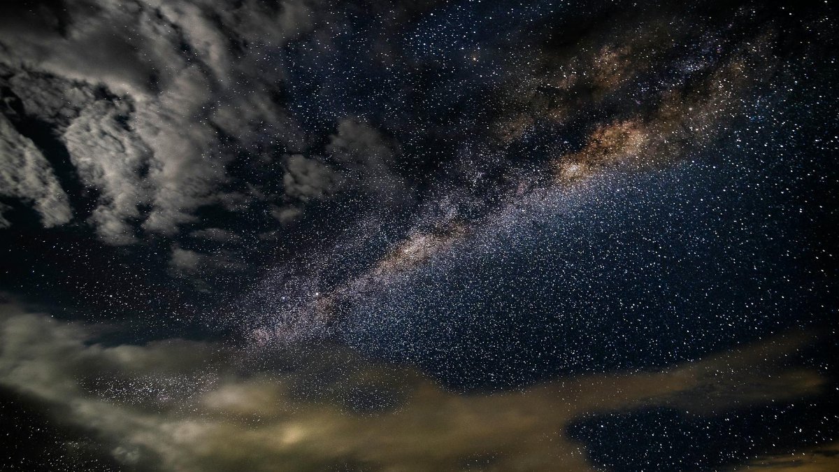 A breathtaking photo capturing the Milky Way galaxy with stars and clouds in a dark, starry sky.