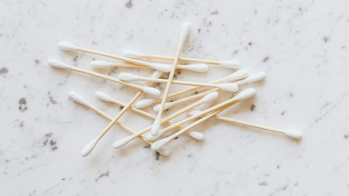 A neat pile of cotton swabs arranged on a white marble surface, highlighting hygiene essentials.