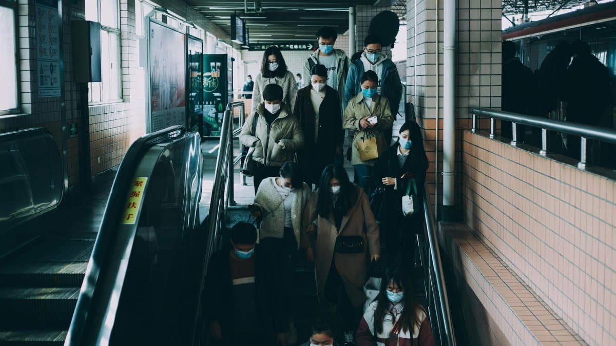 People in masks commuting at a train station in Shanghai during COVID-19. Urban transportation scene.