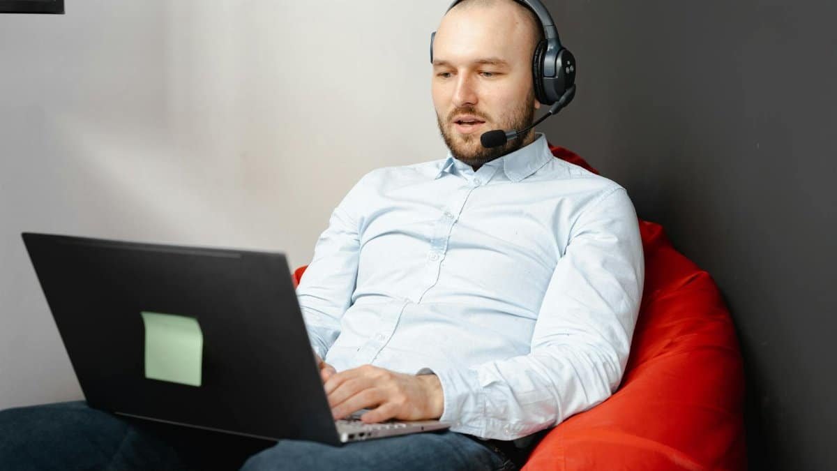 Call center agent working remotely on a laptop with headset and microphone for customer service.