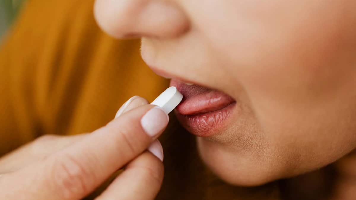 Close-up image of a woman taking a pill, emphasizing health and medication.