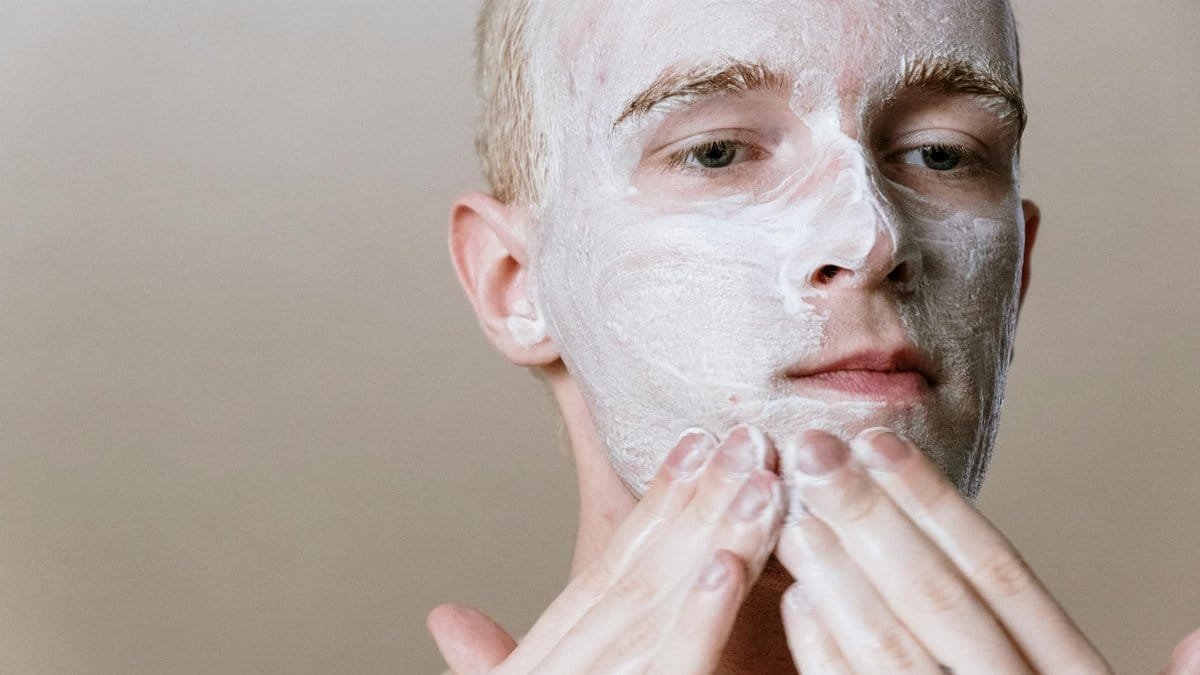 Close-up of a man applying facial cleanser for a refreshing skincare routine, focusing on self-care and health.