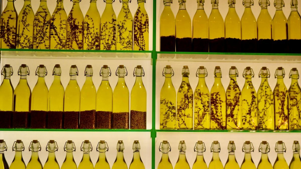 Rows of glass bottles filled with herb and spice infused olive oil on display shelves.
