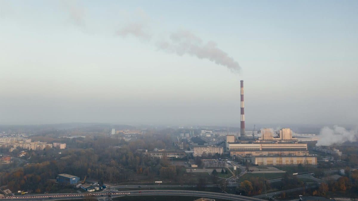 Aerial shot of a power plant emitting smoke, highlighting urban air pollution and industrial impact.