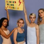 Five women in a studio holding a sign advocating choice, showing empowerment.
