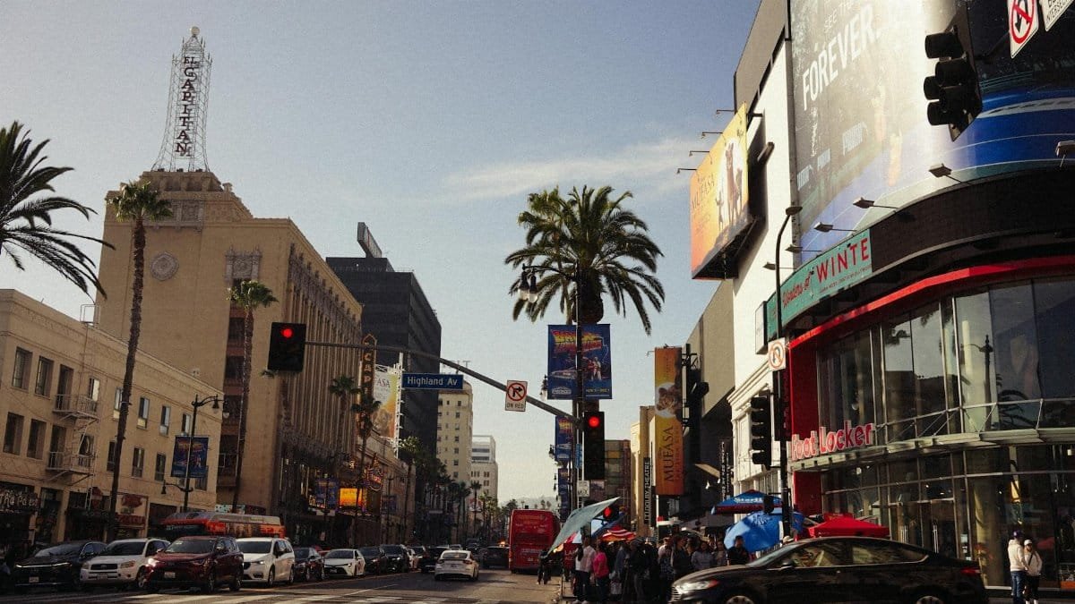 A lively view of Hollywood Boulevard with iconic landmarks and busy street life under a clear sky.