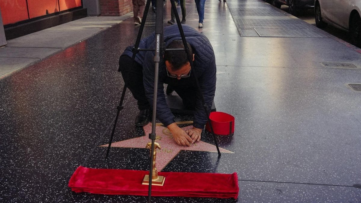A man meticulously cleans a star on the Hollywood Walk of Fame, symbolizing celebrity culture.