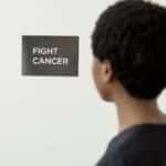 A person looking at a 'Fight Cancer' sign symbolizes cancer awareness.