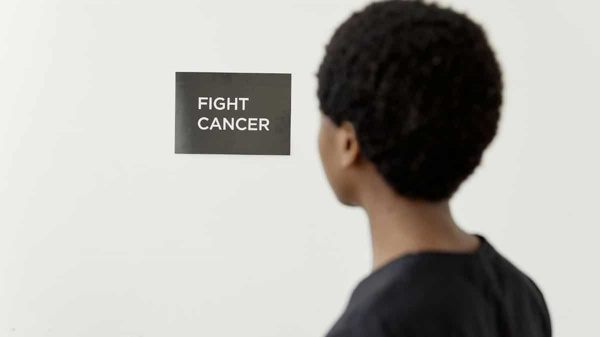 A person looking at a 'Fight Cancer' sign symbolizes cancer awareness.