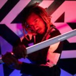 Dynamic portrait of a man posing with neon lights against geometric background.