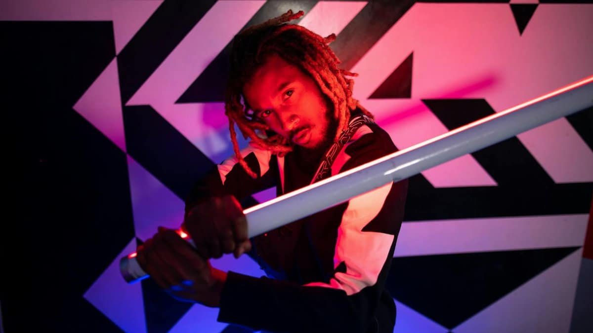 Dynamic portrait of a man posing with neon lights against geometric background.