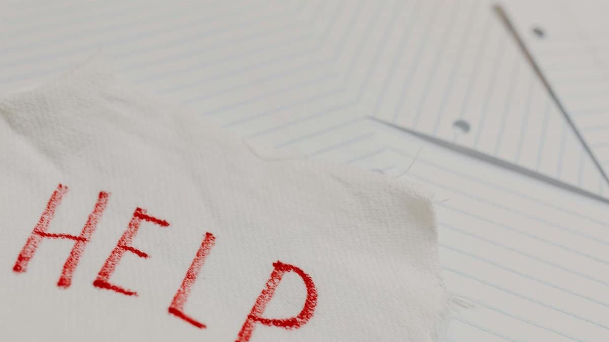 A raw and emotional depiction of a plea for help written on torn paper amidst lined sheets.