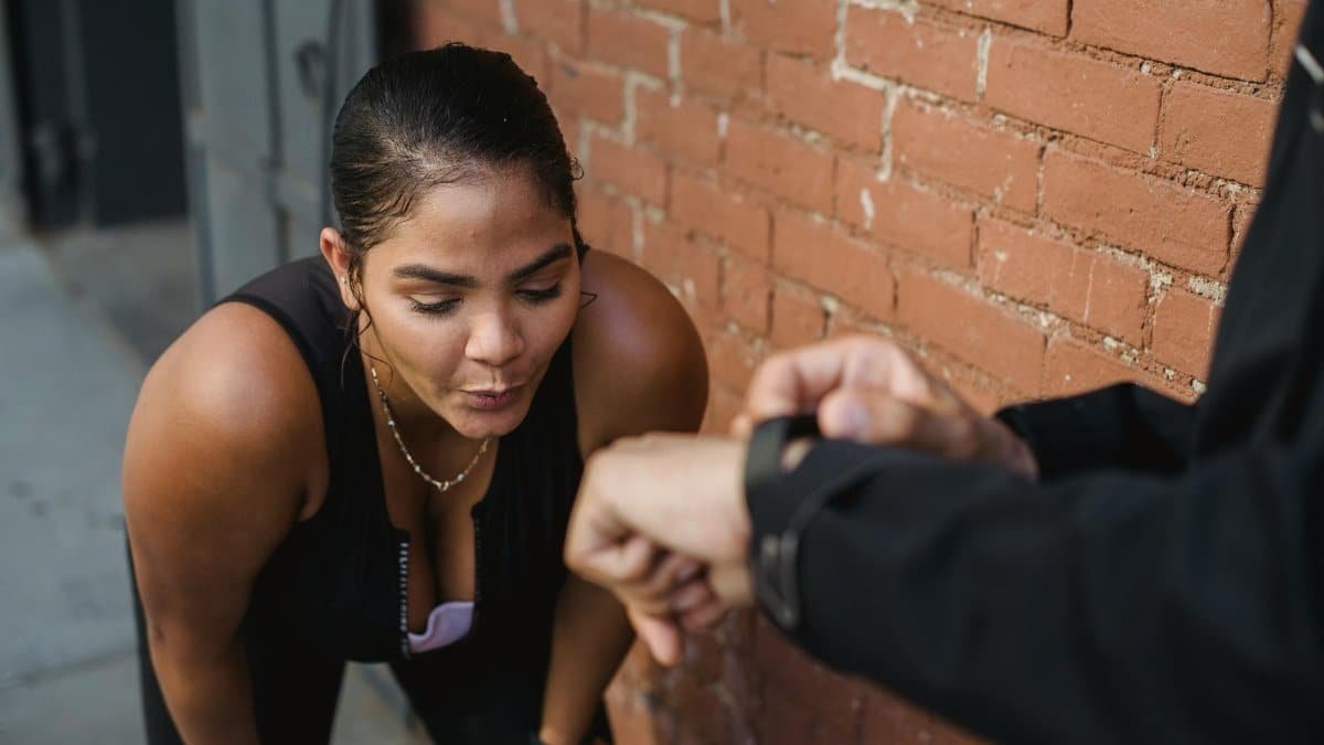 Woman in sportswear catching breath after intense exercise outdoors.